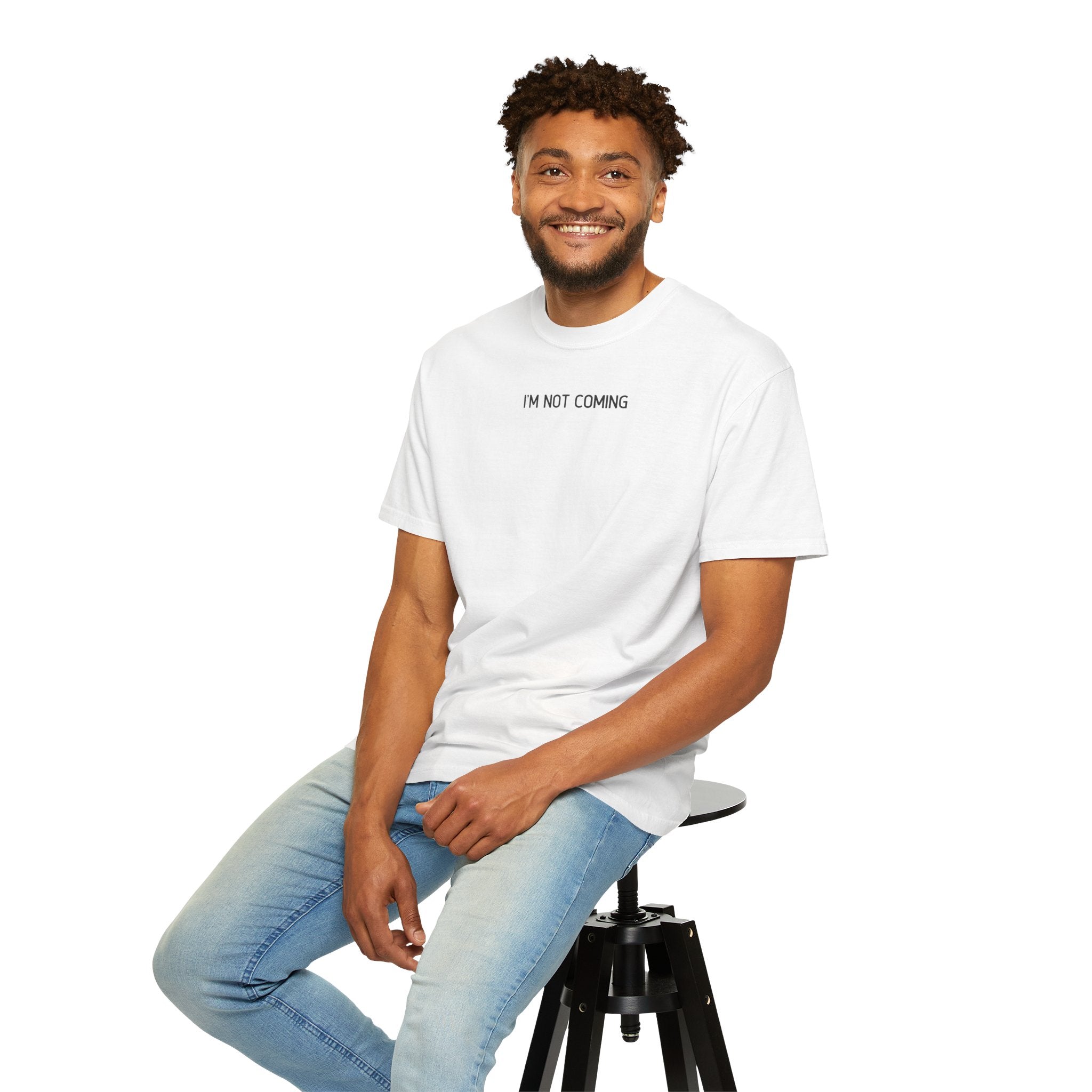 Man sitting on a stool wearing a white t-shirt with text and light blue jeans against a white background