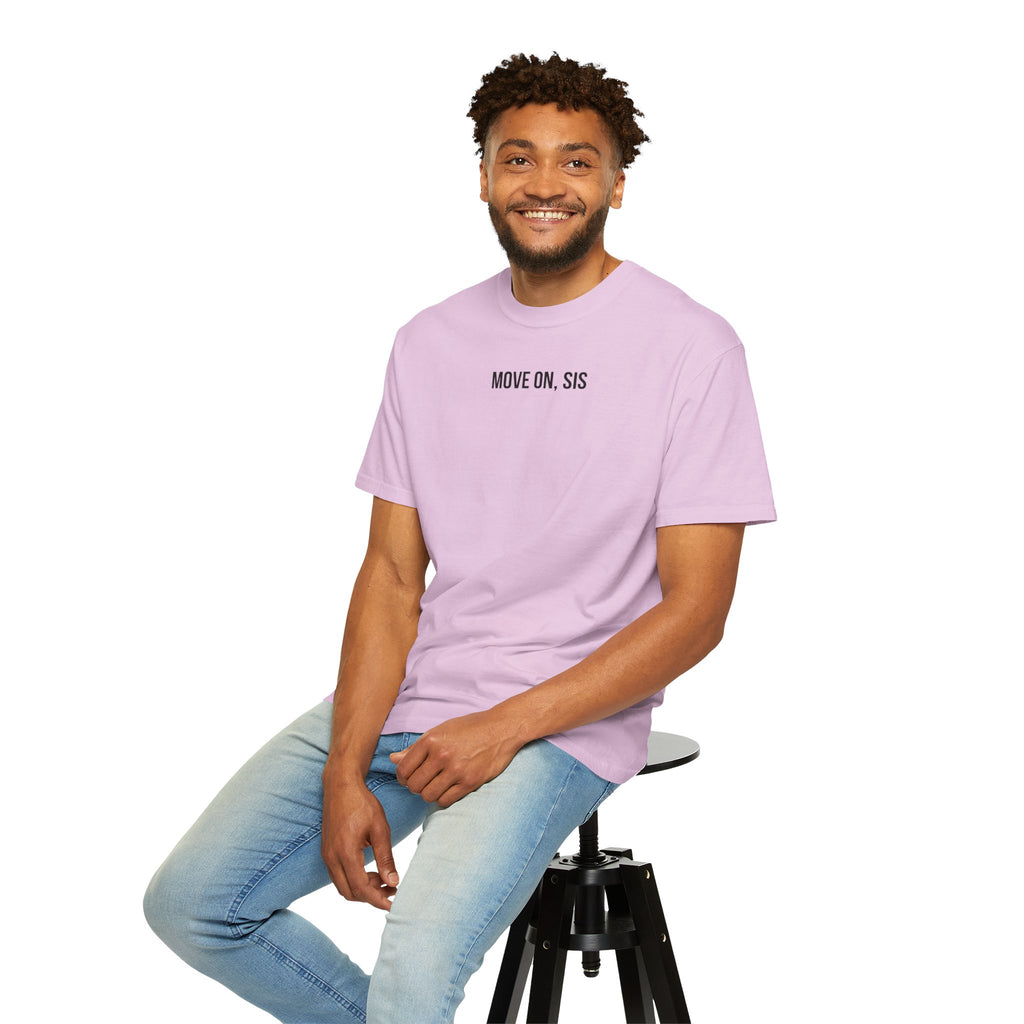 Man wearing a light purple t-shirt with text, sitting on a stool against a white background