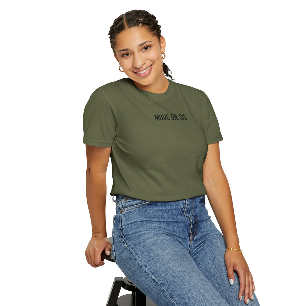 Woman wearing a green t-shirt with 'MOVE ON' text and blue jeans, sitting on a stool against a white background.